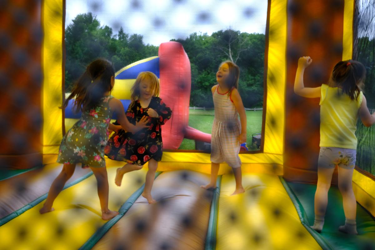 Four children jump in a yellow bounce house
