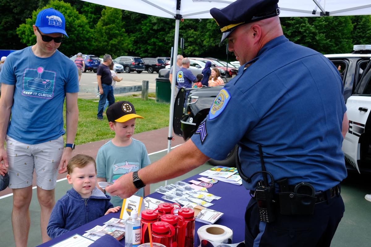 A police officer in uniform offers a badge to a child.